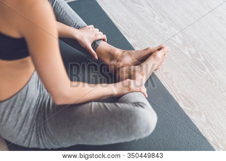 Close Up Photo Of Young Woman In Sportswear Sitting On Youga Mat In Living Room And Doing Butterfly 