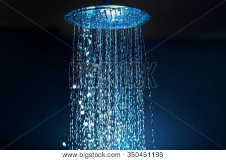 Water Falling From The Shower On A Dark Background With Blue Backlight In The Aqua Zone.
