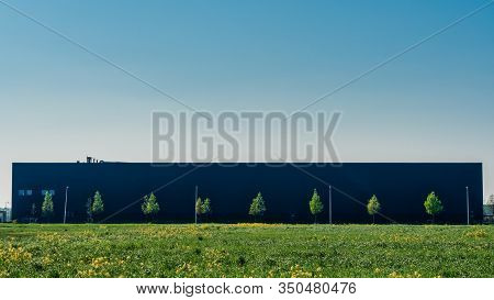 Newly Build Warehouse With Trees In Front Under A Blue Sky