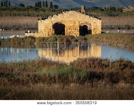 A Ruined Building Reflecting Into The Water With Birds On Top Of It