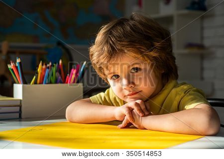 Portrait Of Elementary Pupil Looking At Camera. Cute Child Boy In Classroom Near Blackboard Desk. Ha