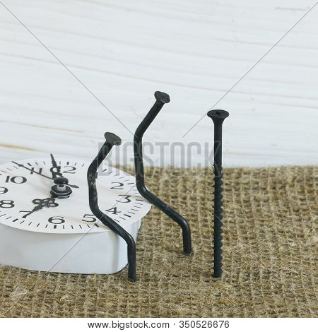 Figurines Of Man Made Of Carpentry Nails. Sit Next To Each Other. Before Them Stands A Nail.