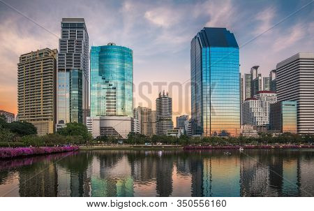 Skyscrapers Reflected In A Lake At Twilight. Benjakiti Park In Bangkok, Thailand