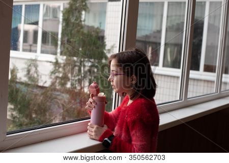 Girl With Cup. Schoolgirl Girl In Glasses Drinks Water From A Thermomug.a Schoolgirl Drinks Tea, Jui