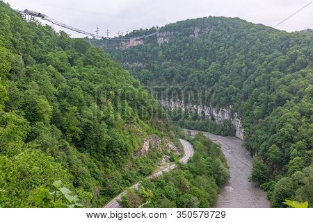 A Gorge In The Mountains With A Suspension Bridge Over It. Skybridge Suspension Bridge Over A Precip