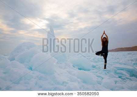 Girl In Winter Time Doing Yoga At Ice Hummock In Frozen Lake Kapchagai Near Almaty, Kazakhstan