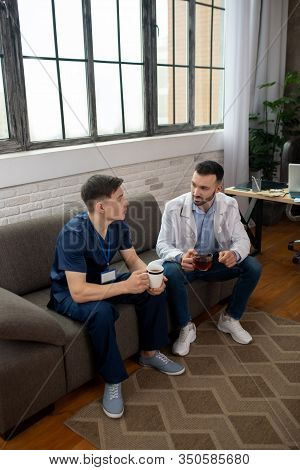 Two Doctors Having Tea And Talking During Changeover