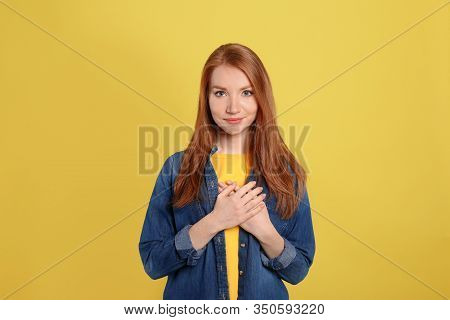Beautiful Grateful Woman With Hands On Chest Against Yellow Background