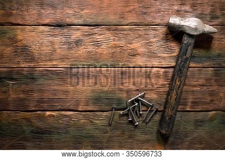 Hammer And Nails On Wooden Brown Workbench Background With Copy Space.