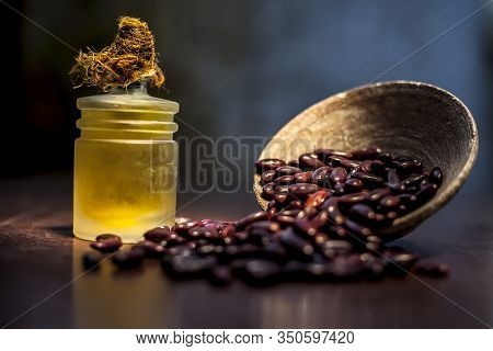 Close Up Of Raw Kidney Beans On Brown Colored Surface In A Clay Bowl And Its Oil In A Small Transpar