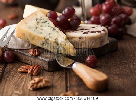 Selection Of Various Cheese On The Board And Grapes On Wooden Table Background. Blue Stilton, Red Le