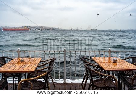 Two Tables At An Outdoor Cafe On The Seafront In The Cold Season Against The Sea Waves Seagull In Th