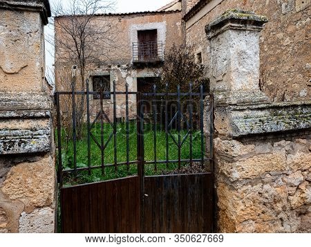 Entrance With A Rusty Iron Door From A Stone House With An Herb Garden In Maderuelo In Spain
