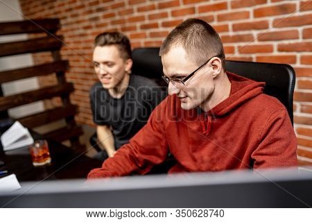 Business People Talking In The Middle Of The Workday. Looking At The Monitor With Happy Smiles. Coll
