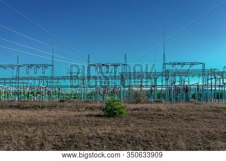 Modern Electric Power Substation In Poland With A Bare Field And One Single Green Bush In The Foregr