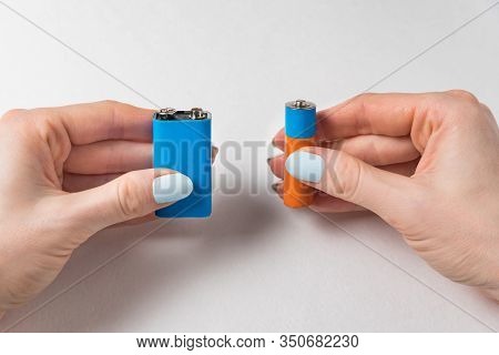 Female Hands Two Batteries On A White Background. Generic Aa And Pp3 Battery And Accumulator.