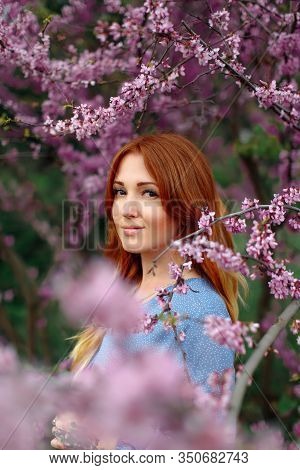 Beautiful Smilling Redhead Woman In Spring Time Blossom Cherrytrees Garden.