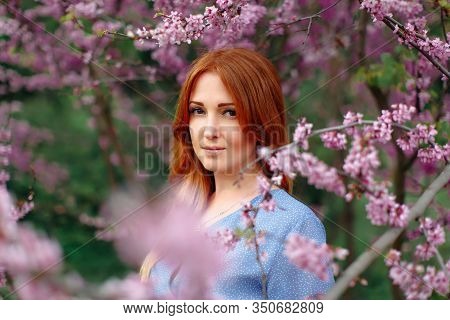 Beautiful Smilling Redhead Woman In Spring Time Blossom Cherrytrees Garden.