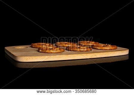 Group Of Six Whole Salty Brown Pretzel On Bamboo Cutting Board Isolated On Black Glass