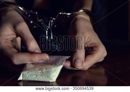 Handcuffed Hands Holding A Bag Of Drugs Close Up