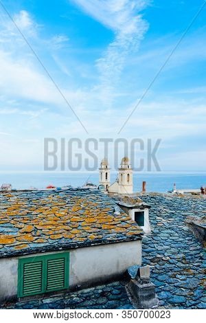 the characteristic twin bell towers of the Saint-Jean Baptiste Church in Bastia, Corsica, France, highlighting above the old slate rooftops of the old town, and the Mediterranean sea in the background