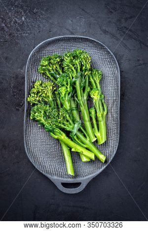 Fresh rapini broccoli rabe as top view on a black plate with copy space 