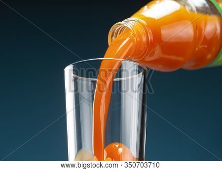 Carrot Juice Is Poured From A Bottle Into A Glass
