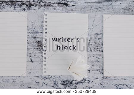 Piece Of Paper On Wooden Desk With Writer's Block Text Surrounded By Blank Notepads And With With Sc