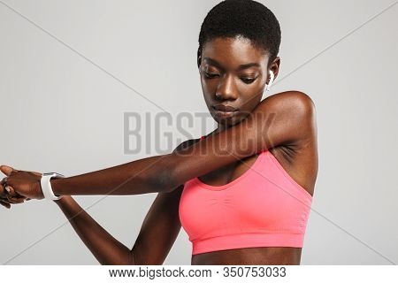 Image of african american sportswoman using wireless earbuds while working out isolated over white background