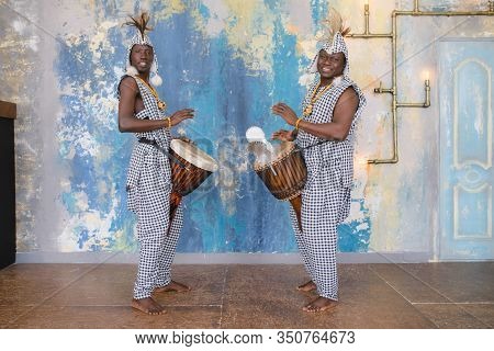 A Group Of People In Traditional African Costumes Playing Jembe Drums