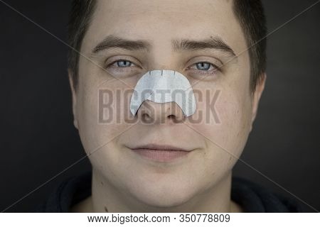 A Man Puts On And Removes A Strip For The Nose From Black Dots. Coal Cleaning Strips From Blackheads