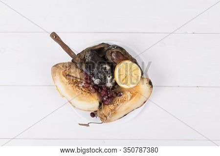 Moldy Melon, Grapes And Avocados On A White Plate With Knife On A White Background, Concept Of Stop 