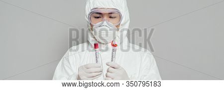 Panoramic Shot Of Asian Epidemiologist In Hazmat Suit And Respirator Mask Holding Test Tubes With Bl