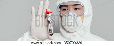 Panoramic Shot Of Asian Epidemiologist In Hazmat Suit And Respirator Mask Showing Test Tube With Blo