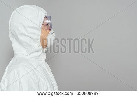 Side View Of Asian Epidemiologist In Hazmat Suit And Respirator Mask Isolated On Grey