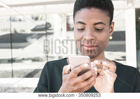 Focused African American Woman Using Online Mobile App. Satisfied Black Lady Holding Using Smartphon