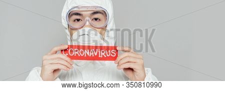 Panoramic Shot Of Asian Epidemiologist In Hazmat Suit And Respirator Mask Holding Warning Card With 