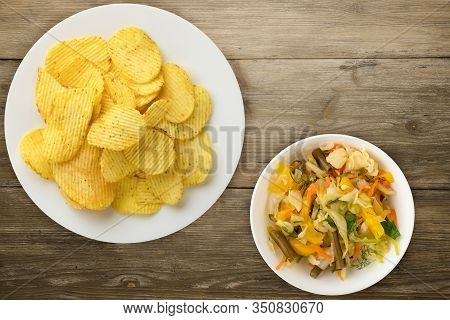 Potato Chips On A White Plate With Vegetarion Salad. Chips On A Wooden Background Top View.