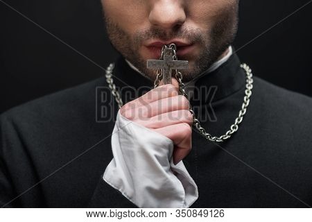 Cropped View Of Catholic Priest Kissing Silver Cross On His Necklace Isolated On Black