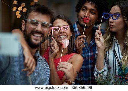 close up of four young multiethnic adults having fun with props on sticks, Fun, joy, crazy, party, friends, couples, multiethnic concept
