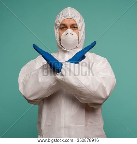 A Male Doctor In Protective Overalls And A Mask Shows Stop Sign. Coronovirus Protection Concept In C