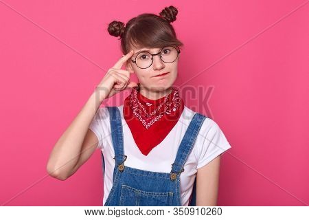 Close Up Portrait Of Attarctive Pensive Young Female Wearing White Casual T Shirt, Overalls And Red 