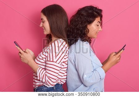 Close Up Portrait Of Two Cute Young Women Pose Together Isolated Over Pink Background While Standing