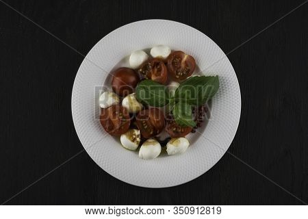 Delicious Salad With Cherry Tomatoes Mozzarella And Basil In A Bowl On A Black Wooden Table