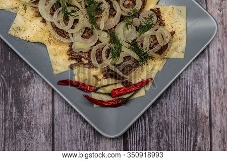 Beshbarmak Is A National Tatar Dish - Square Pasta With Boiled Meat And Onions. On A Black Backgroun