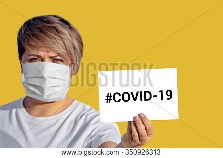 Woman In Face Mask Hold Blank With Inscription Covid-19. World Health Organization Who Introduced Ne