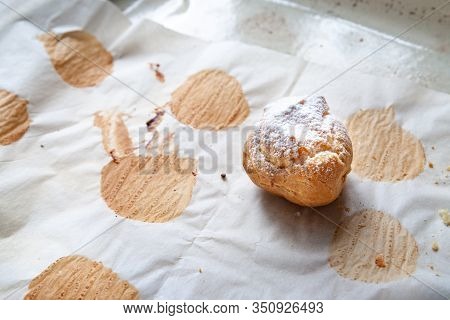 Homemade Baking. A Freshly Baked Hot Sweet Burger Sprinkled With Icing Sugar Lies On Baking Paper On
