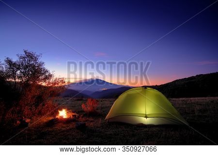 illuminated tent, campfire and Etna Mount from Nebrodi Park at twilight, Sicily