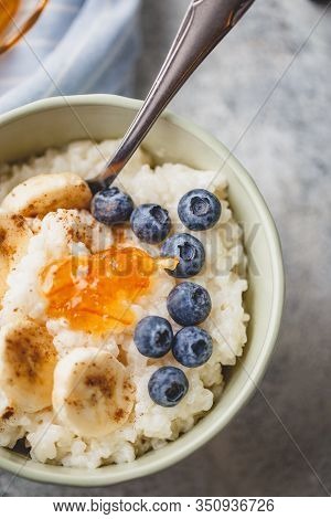 Close Up Of Bowl Breakfast With Milk Rice Porridge With Banans, Blueberry, Cinnamon And Orange Jam, 
