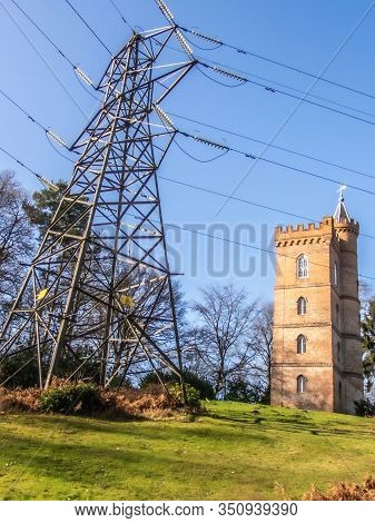 Painshill Park, Cobham Surrey, England. February 11 2020 Gothic Tower Behind Modern Electricity Pylo